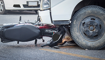 A motorcycle rests on the ground adjacent to a ca