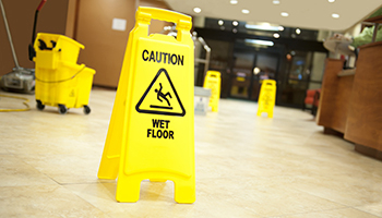 A yellow caution sign placed on the floor in a hotel lobby